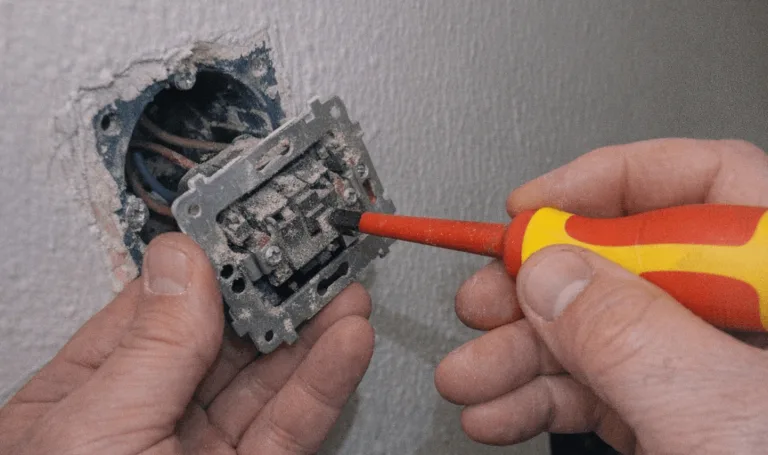 Elektriker prüft eine Steckdose mit einem Multimeter bei sicherer Fehlersuche